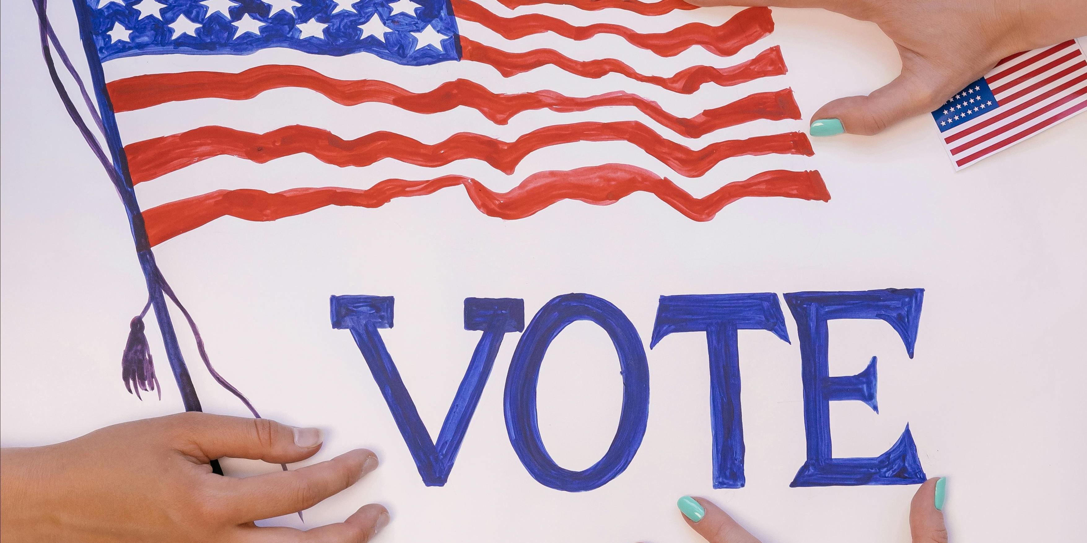 An waving American flag surrounded by small flags and the word Vote with hands surrounding the flag
