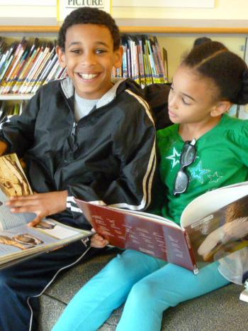 two children looking at books in a library 
